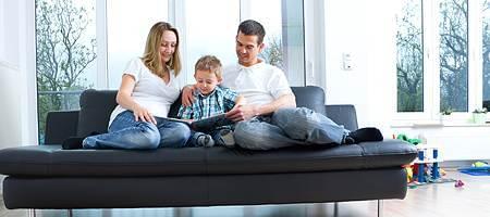 Family on couch in front of living room windows